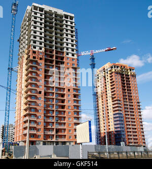 Hoisting crane and house construction against the blue sky Stock Photo