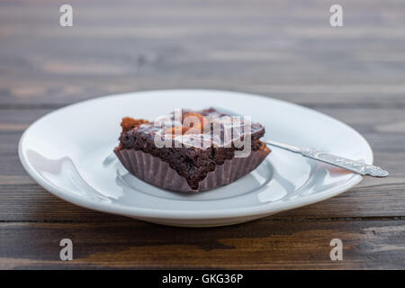 Homemade chocolate brownie with almond and spoon in white dish on wood table. Stock Photo