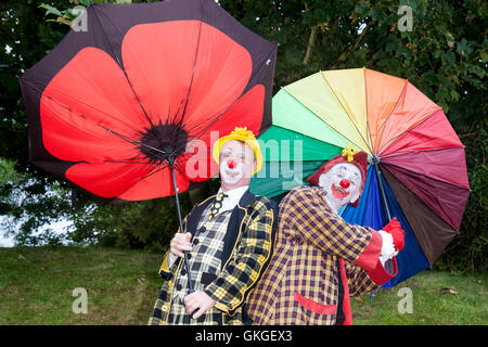 Southport, Merseyside. UK Weather: 20th August  2016.Weather:  As the high winds and gales hit resort, Sonny & Rainbow struggle to hold on to their umbrellas.  As two of the funniest clowns around, Gordon Murray and Gary McBeth,  can turn everyday situations into funny scenarios.  The crowds were blown away by their antics as the bad weather struck once again over the crowds at the Southport Flower Show.  Credit:  Cernan Elias/Alamy Live News Stock Photo