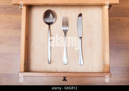above view of table knife, fork, spoon in open drawer of nightstand Stock Photo