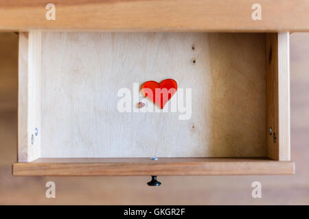 above view of little and big glass hearts in open drawer of nightstand Stock Photo