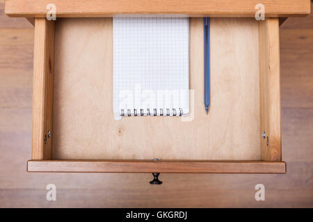 top view of blue pen and squared notebook in open drawer of nightstand Stock Photo