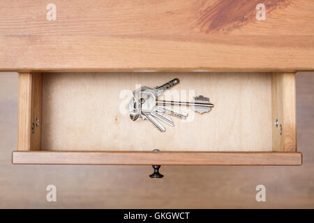 top view of bunch of door keys on ring in open drawer of nightstand Stock Photo