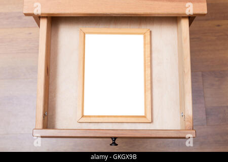 top view of simple picture frame with cut out canvas in open drawer of nightstand Stock Photo