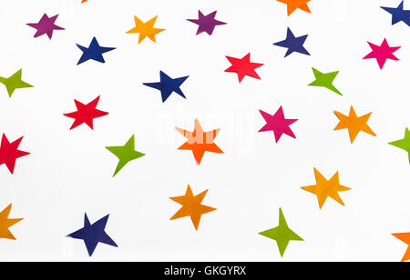 various stars carved by hand from colored paper on white background Stock Photo