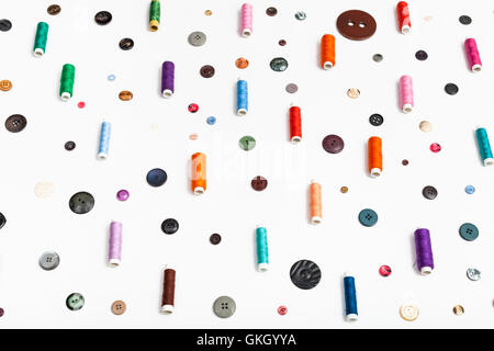 side view of spools of thread and various buttons on white background Stock Photo