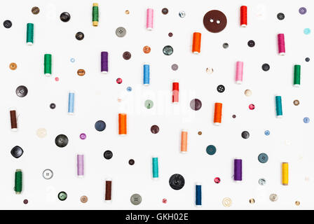 many spools of thread and various buttons on white background Stock Photo