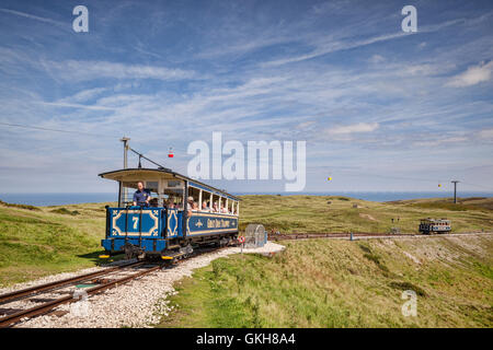 A passenger car of the Great Orme Tramway climbs from the upper passing loop as the descending car continues down, on Great Orme Stock Photo