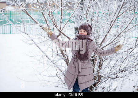 Snowfall, portrait of a happy little girl on the background of a winter park Stock Photo