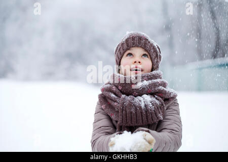 Snowfall, portrait of a happy little girl on the background of a winter park Stock Photo