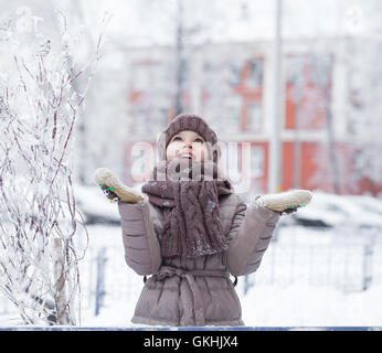 Snowfall, portrait of a happy little girl on the background of a winter park Stock Photo