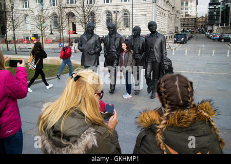 female tourists taking photos at The Beatles statue sculpture at Pier Head on Liverpools waterfront Stock Photo