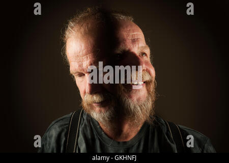Head portrait with double exposure of an older man with a beard against black background. Stock Photo