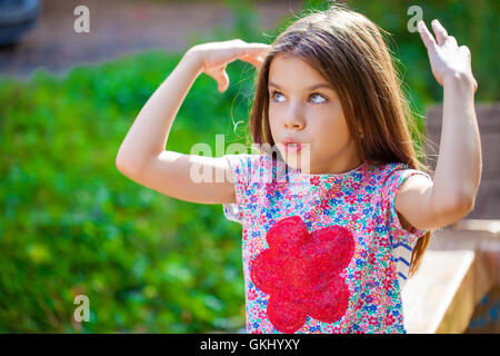 Cheerful 11 year old girl wearing pink t-shirt and black pants with waving  long blond hair dancing. isolated on grey background Stock Photo