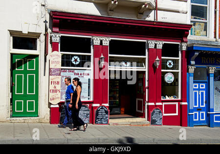 Couple walking past fish & chip shop in Scarborough, North Yorkshire, England UK Stock Photo