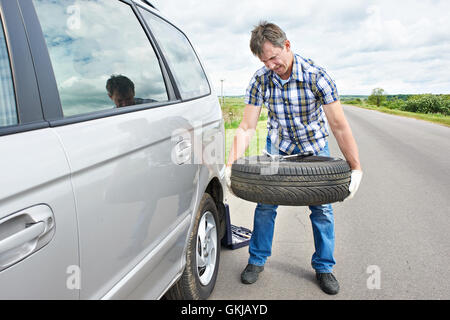 Man changing a spare tire of car on road Stock Photo