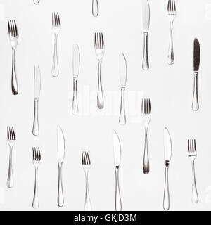 table knives and forks arranged on white square background Stock Photo