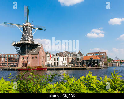 Windmill Adriaan and people on waterfront cafe alongside Spaarne river in Haarlem, Holland, Netherlands Stock Photo