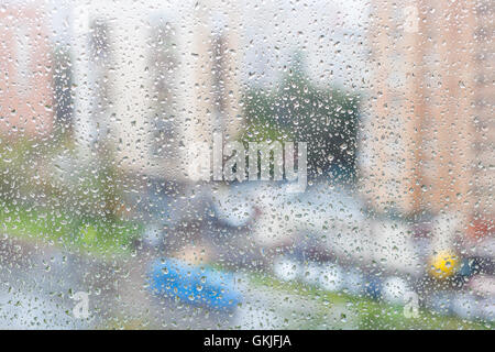 rainy weather in city - view of raindrops on windowpane of urban house Stock Photo