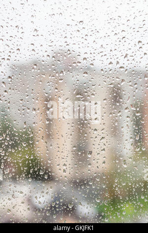 rainy weather in city - view of raindrops on window of apartment house Stock Photo
