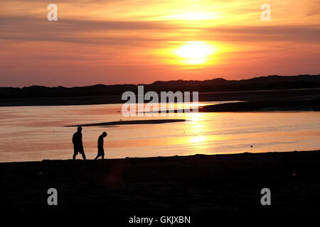 two people on beach at sunset in silhouette Stock Photo