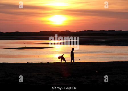 two people on beach at sunset in silhouette Stock Photo
