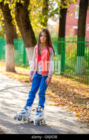 little young girl go on roller skates, outdoor, in the evening summer Stock Photo