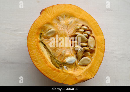 Pumpkin cut in half with seeds, on a wood background, La Reunion Stock Photo