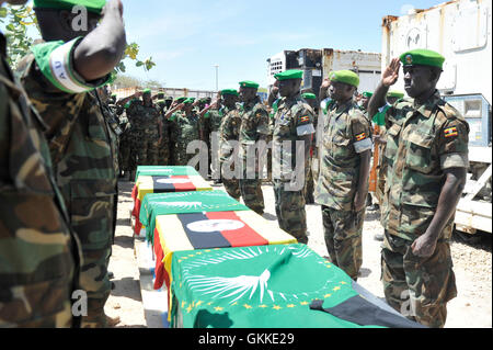 AMISOM UPDF soldiers salute their fallen comrades during the repatriation ceremony of 3 AMISOM soldiers who died during the attack on the Somalia parliament building by Alshabaab terrorists on 24th May 2014 in Mogadishu. AMISOM Public Information Services / David Mutua Stock Photo