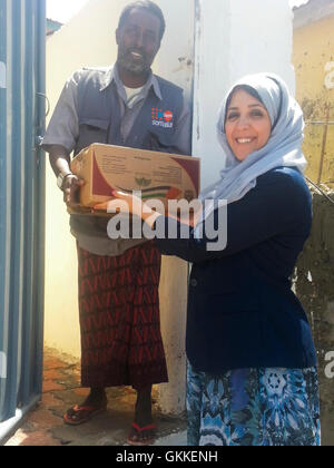 AMISOM's Woman & Child Protection Office, Kaoutar Kaddouri, hands a box of dates to a man during a distribution of dates to less fortunate families around Mogadishu by the AMISOM Gender Unit on 3rd July 2014. The dates were given to the Unit by the Embassy of the United Arab Emirates. AMISOM Photo Stock Photo