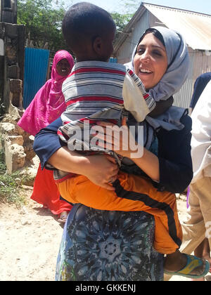 AMISOM's Woman & Child Protection Office, Kaoutar Kaddouri,  holds a young boy during a distribution of dates to less fortunate families around Mogadishu by the AMISOM Gender Unit on 3rd July 2014. The dates were given to the Unit by the Embassy of the United Arab Emirates. AMISOM Photo Stock Photo