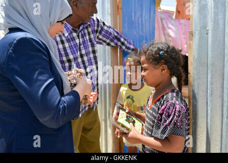 AMISOM's Woman & Child Protection Office, Kaoutar Kaddouri,  hands a box of dates to children during a distribution of dates to less fortunate families around Mogadishu by the AMISOM Gender Unit on 3rd July 2014. The dates were given to the Unit by the Embassy of the United Arab Emirates. AMISOM Photo Stock Photo