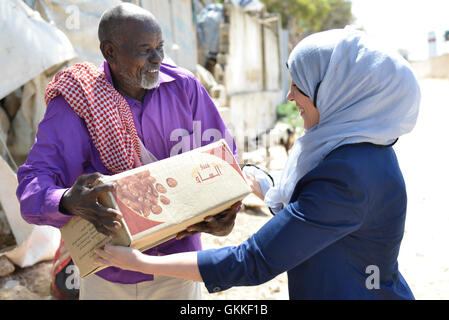 AMISOM's Woman & Child Protection Office, Kaoutar Kaddouri, hands a box of dates to a man during a distribution of dates to less fortunate families around Mogadishu by the AMISOM Gender Unit on 3rd July 2014. The dates were given to the Unit by the Embassy of the United Arab Emirates. AMISOM Photo Stock Photo