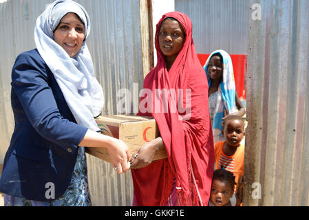 AMISOM's Woman & Child Protection Office, Kaoutar Kaddouri,  hands a box of dates to a lady during a distribution of dates to less fortunate families around Mogadishu by the AMISOM Gender Unit on 3rd July 2014. The dates were given to the Unit by the Embassy of the United Arab Emirates. AMISOM Photo Stock Photo