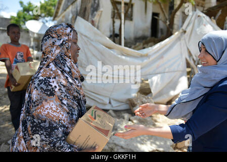 AMISOM's Woman & Child Protection Office, Kaoutar Kaddouri,  hands a box of dates to a lady during a distribution of dates to less fortunate families around Mogadishu by the AMISOM Gender Unit on 3rd July 2014. The dates were given to the Unit by the Embassy of the United Arab Emirates. AMISOM Photo Stock Photo