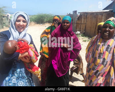 AMISOM's Woman & Child Protection Office, Kaoutar Kaddouri, holds a child during a distribution of dates to less fortunate families around Mogadishu by the AMISOM Gender Unit on 3rd July 2014. The dates were given to the Unit by the Embassy of the United Arab Emirates. AMISOM Photo Stock Photo