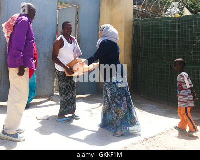 AMISOM's Woman & Child Protection Office, Kaoutar Kaddouri, hands a box of dates to a man during a distribution of dates to less fortunate families around Mogadishu by the AMISOM Gender Unit on 3rd July 2014. The dates were given to the Unit by the Embassy of the United Arab Emirates. AMISOM Photo Stock Photo