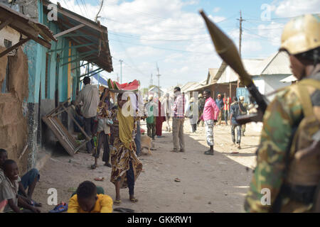 A young girl carries watermelon on her head, as a Burundian soldier belonging to the African Union Mission in Somalia, patrols through Mahaday town in the Middle Shabelle region of Somalia. AMISOM Photo / Tobin Jones Stock Photo