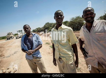 SOMALIA, Mogadishu: In a photgraph taken 24 January and released by the African Union-United Nations Information Support Team 26 January, Somali men look on as African Union Mission in Somalia (AMISOM) combat engineers grade and repair a stretch of road leading to the town of Afgooye in Somalia's Lower Shabelle region along the main route linking the fertile, agricultural region with the capital Mogadishu. After years under the control of the violent extremist Al-Qaeda linked group Al Shabaab, stretches of the economically  important thoroughfare were virtually in-passable. Now, 7 months after Stock Photo