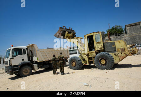 SOMALIA, Mogadishu: In a photograph taken and released by the African Union-United Nations Information Support Team 29 January, Ugandan soldiers serving with the African Union Mission in Somalia (AMISOM) look on while an earth-mover operated by AMISOM combat engineers clears sand, debris and rubble from an area known as El-Gabta or 'Peace Gardens' in central Mogadishu. El Gabta will eventually become an open-air park area and gardens for people to use and relax in. The work is being carried out as part of a week-long programme of activities called Tarehe Sita, meaning the 6th day in Kiswahili, Stock Photo