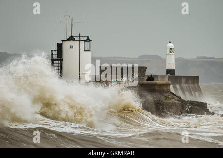 People watch stormy conditions on the harbour wall at Porthcawl, Wales, where windy conditions and high tides are still prevalent across the UK. Stock Photo