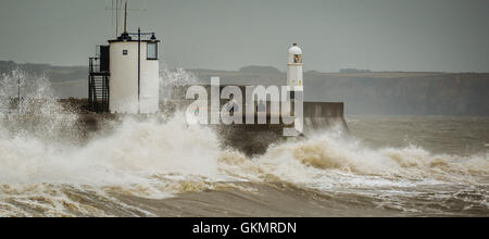 People watch stormy conditions on the harbour wall at Porthcawl, Wales, where windy conditions and high tides are still prevalent across the UK. Stock Photo