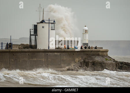 People watch stormy conditions on the harbour wall at Porthcawl, Wales, where windy conditions and high tides are still prevalent across the UK. Stock Photo