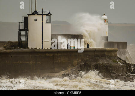 People watch stormy conditions on the harbour wall at Porthcawl, Wales, where windy conditions and high tides are still prevalent across the UK. Stock Photo