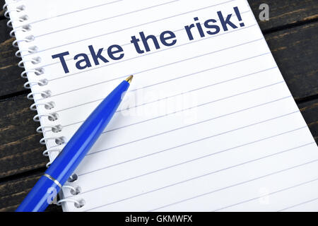 Take the risk text on notepad and blue pen Stock Photo