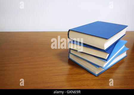 Books stack on a wooden desk table with blank empty cover and copyspace. Stock Photo