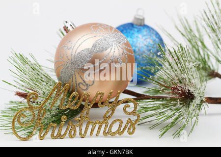 Merry Christmas written with golden letters, pine and two Christmas baubles Stock Photo