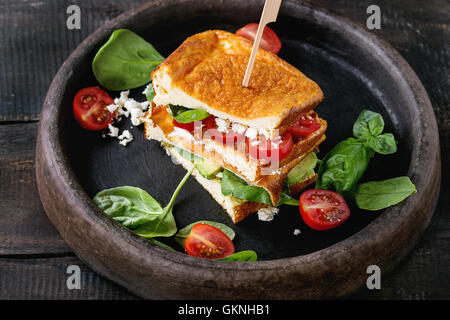 Low-carb gluten free Cloud bread veggie sandwich with spinach, avocado, feta cheese, tomatoes and pesto sauce, served on clay tr Stock Photo