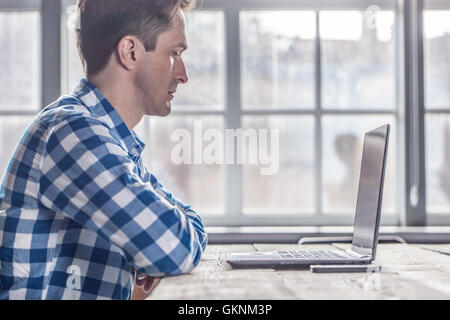 Man in casual clothes using a laptop computer in office Stock Photo