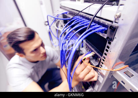 Young engeneer man in network server room connecting wires Stock Photo